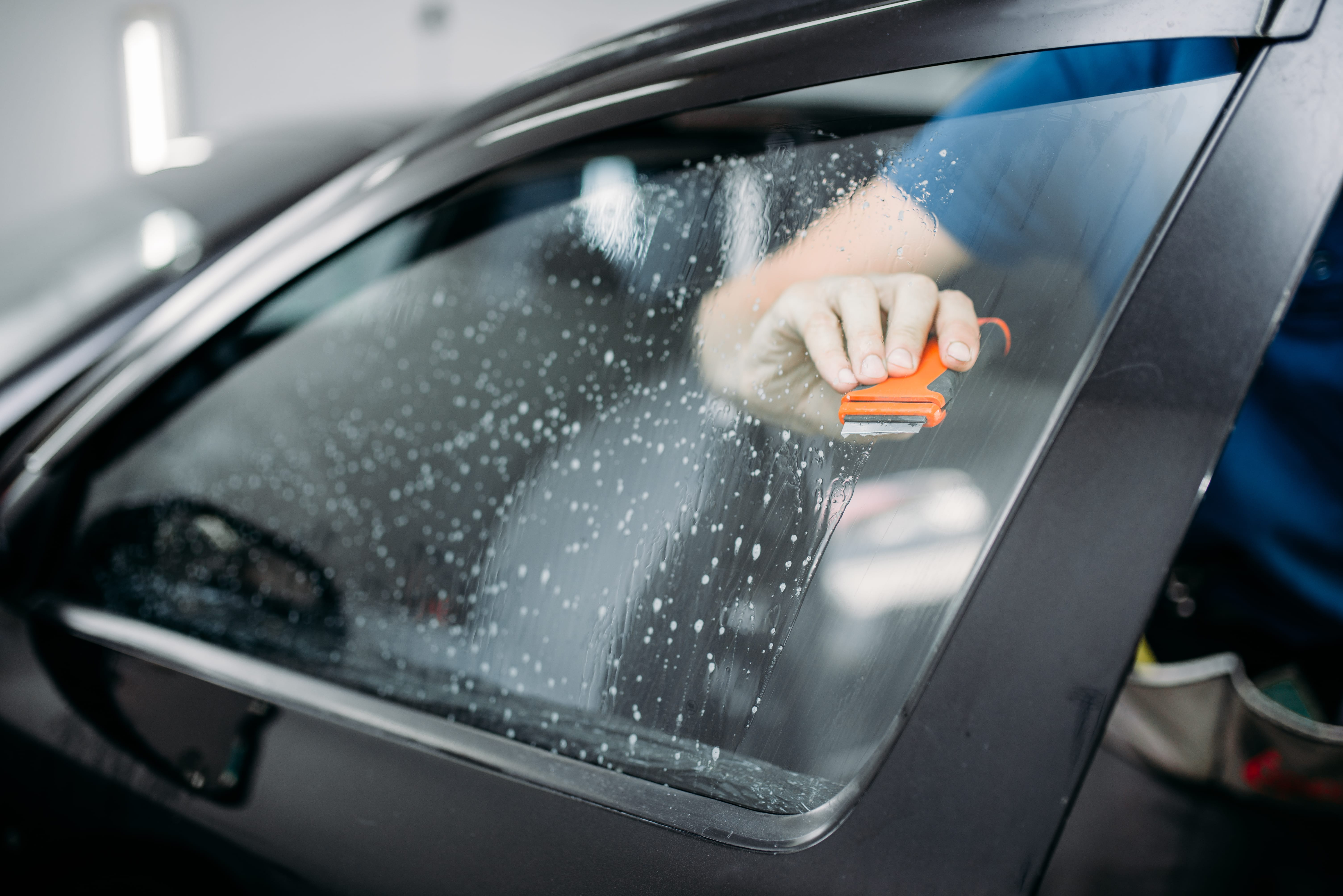 Technician smoothing film on a vehicle window